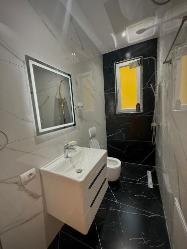 a black and white bathroom with a sink and a toilet at Selami GuestHouse in Peshkopi