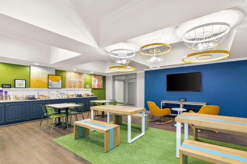 a waiting area with tables and chairs in a cafeteria at Spark by Hilton Commerce, GA in Commerce