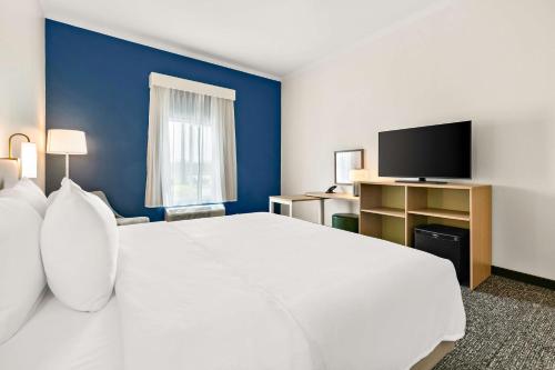 a hotel room with a large white bed and a tv at Spark by Hilton Commerce, GA in Commerce