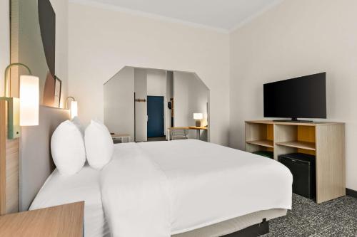 a bedroom with a large white bed and a tv at Spark by Hilton Commerce, GA in Commerce