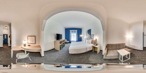 a hotel room with a bedroom with a bed and a couch at Spark by Hilton Commerce, GA in Commerce
