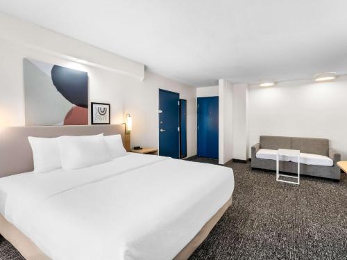 a bedroom with a large white bed and a couch at Spark by Hilton Augusta in Augusta