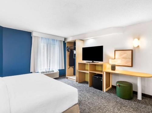 a hotel room with a bed and a desk with a television at Spark by Hilton Augusta in Augusta