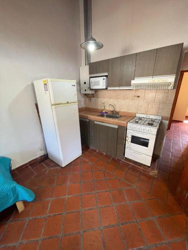 a kitchen with a white refrigerator and a stove at Cabañas Terrazas del Sol in Villa Carlos Paz