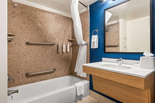 a bathroom with a tub and a sink and a mirror at Spark by Hilton Port Wentworth Savannah in Port Wentworth