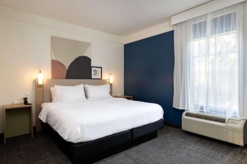 a bedroom with a large white bed and a blue wall at Spark by Hilton Savannah Airport in Savannah