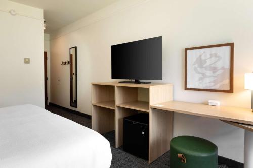 a hotel room with a bed and a desk with a television at Spark by Hilton Savannah Airport in Savannah