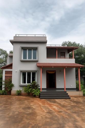 a white house with a driveway in front of it at Skandasiri Hampi homestay in Sandūr