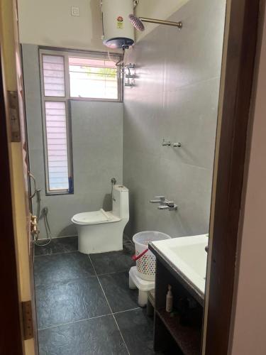 a white bathroom with a toilet and a sink at Skandasiri Hampi homestay in Sandūr