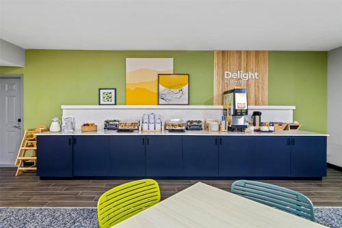 a cafeteria with a blue counter and yellow chairs at Spark By Hilton Merrillville in Merrillville