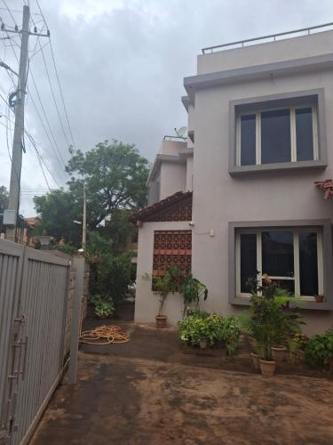 a white house with a fence in front of it at Skandasiri Hampi homestay in Sandūr