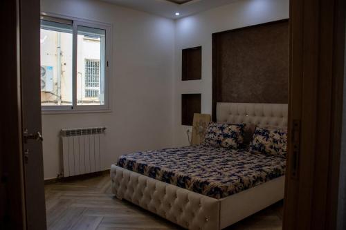 a bedroom with a bed in a room with a window at Villa 3 niveau avec jacuzzi, terrasse et cour in Birkhadem