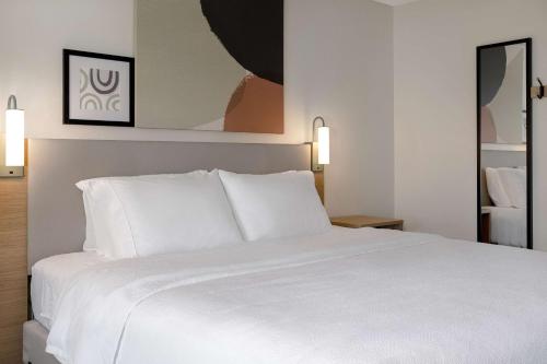 a white bed with white pillows in a hotel room at Spark By Hilton Evansville East, In in Evansville