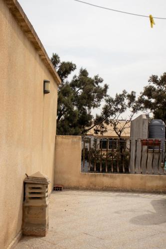 a building next to a fence with trees in the background at Villa 3 niveau avec jacuzzi, terrasse et cour in Birkhadem