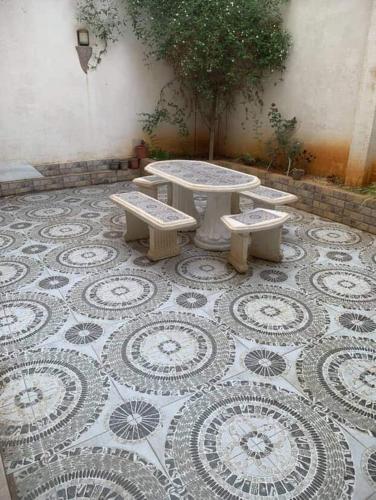 a table and four benches on a tiled floor at Villa 3 niveau avec jacuzzi, terrasse et cour in Birkhadem