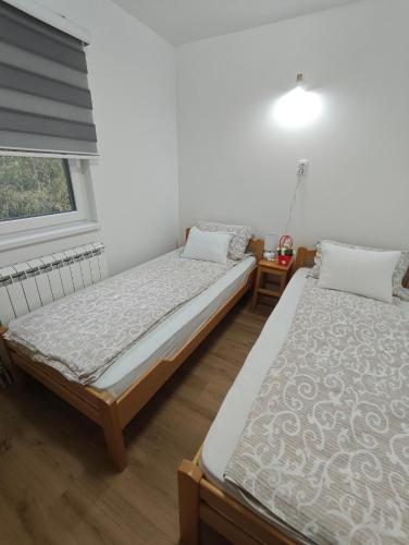 two twin beds in a room with a window at Jovičića Kuća in Mokra Gora