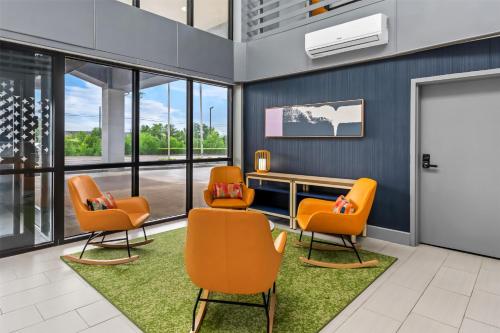 a waiting room with orange chairs and a desk at Spark by Hilton Lexington Hamburg in Lexington