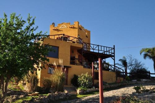 a yellow building with a balcony on top of it at Cabañas Terrazas del Sol in Villa Carlos Paz