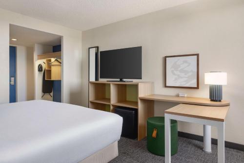 a hotel room with a bed and a desk with a television at Spark By Hilton Germantown Washington Dc North in Germantown