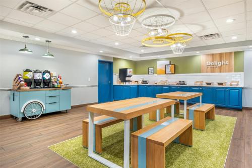シェファーズビルにあるSpark by Hilton Shepherdsville Louisville Southの青いキャビネットとテーブル、キッチンを備えたカフェテリア