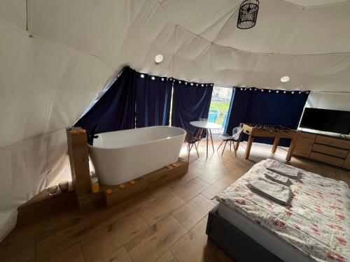 a tub in a tent with a bed and a table at Glamp Ojcowska in Jerzmanowice