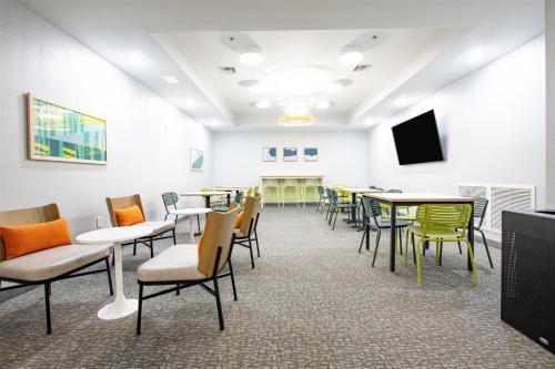 a waiting room with tables and chairs and a flat screen tv at Spark By Hilton Lafayette South in Lafayette