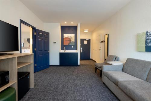 a living room with a couch and a flat screen tv at Spark by Hilton Hammond in Hammond