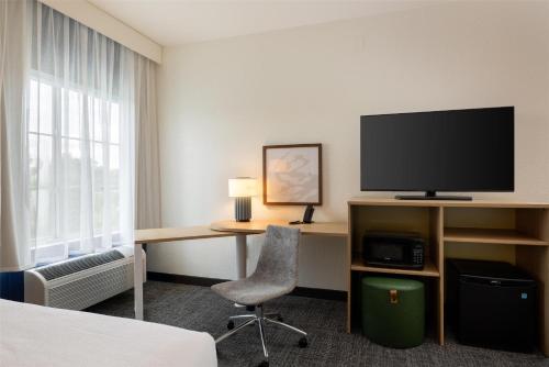 a hotel room with a desk with a tv and a chair at Spark by Hilton Hammond in Hammond