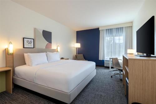 a hotel room with a bed and a desk and a television at Spark by Hilton Hammond in Hammond