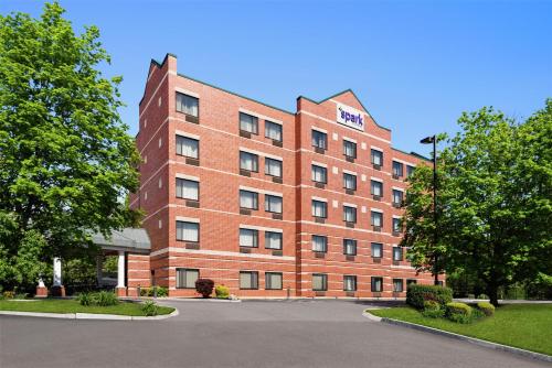 a red brick building with trees in front of it at Spark by Hilton Woburn Boston in Woburn