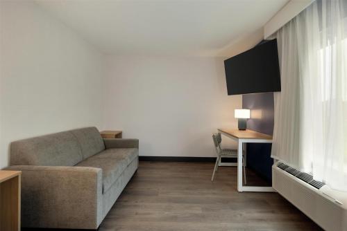 a living room with a couch and a tv at Spark by Hilton Woburn Boston in Woburn