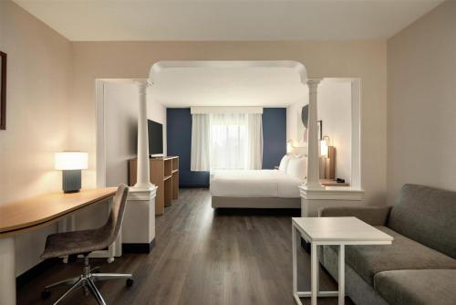 a hotel room with a bed and a couch and a desk at Spark by Hilton Woburn Boston in Woburn