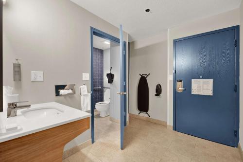 a bathroom with a blue door and a sink and a toilet at Spark by Hilton Plymouth in Plymouth
