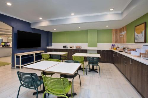 a cafeteria with tables and chairs and a flat screen tv at Spark by Hilton Walker Grand Rapids North in Grand Rapids