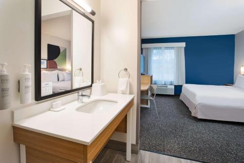 a bathroom with a sink and a bed and a mirror at Spark by Hilton Walker Grand Rapids North in Grand Rapids