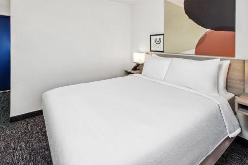 a hotel room with a white bed with pillows at Spark by Hilton Rochester South in Rochester
