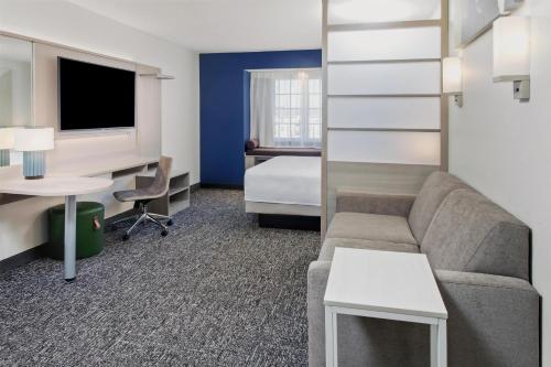 a hotel room with a couch and a desk and a bed at Spark by Hilton Rochester South in Rochester