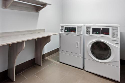 a laundry room with a washer and dryer next to a counter at Spark by Hilton Rochester South in Rochester
