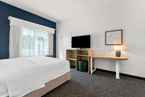 a bedroom with a bed and a desk with a television at Spark By Hilton Tupelo in Tupelo