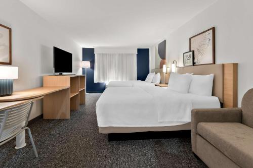 a large hotel room with two beds and a couch at Spark By Hilton Tupelo in Tupelo