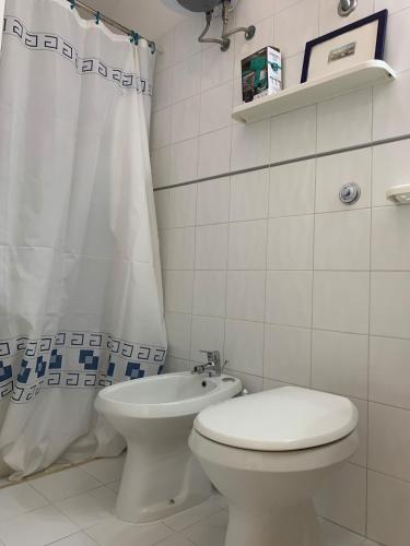 a white bathroom with a toilet and a shower curtain at A 100 m dalla spiaggia in Torre Mozza