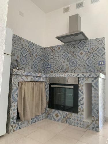 a kitchen with a tv and a tiled wall at A 100 m dalla spiaggia in Torre Mozza