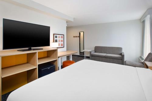 a hotel room with a bed and a flat screen tv at Spark By Hilton Jackson Ridgeland in Jackson