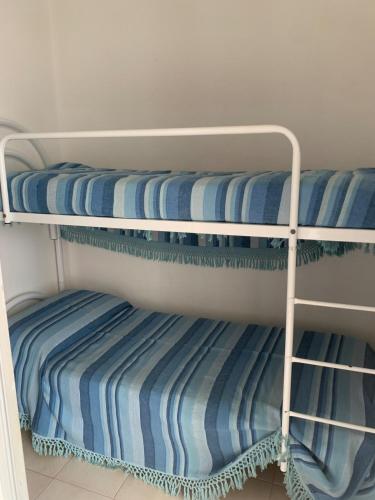 three bunk beds with blue and white striped sheets at A 100 m dalla spiaggia in Torre Mozza