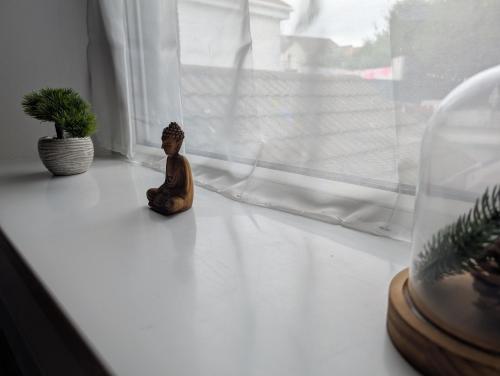 a small figurine sitting on a window sill next to a plant at R4 - New Relaxing Double - City & Beach Access, WIFI, Free Parking - Self Catering in Swansea