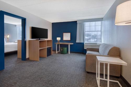a hotel room with a couch and a television at Spark By Hilton Rochester University Area in Rochester