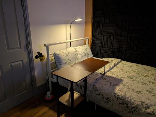 a bedroom with a bed and a table next to a lamp at R4 - New Relaxing Double - City & Beach Access, WIFI, Free Parking - Self Catering in Swansea