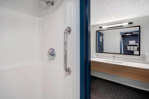 a bathroom with a tub and a sink and a mirror at Spark By Hilton Rochester University Area in Rochester
