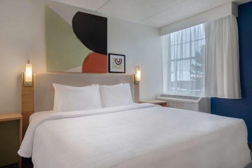 a white bed in a hotel room with a window at Spark By Hilton Rochester University Area in Rochester