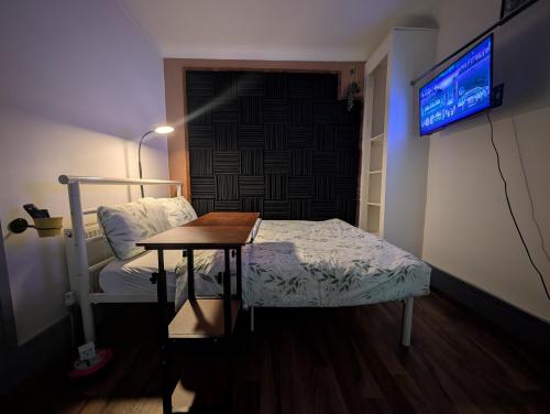 a room with a bed and a table and a tv at R4 - New Relaxing Double - City & Beach Access, WIFI, Free Parking - Self Catering in Swansea